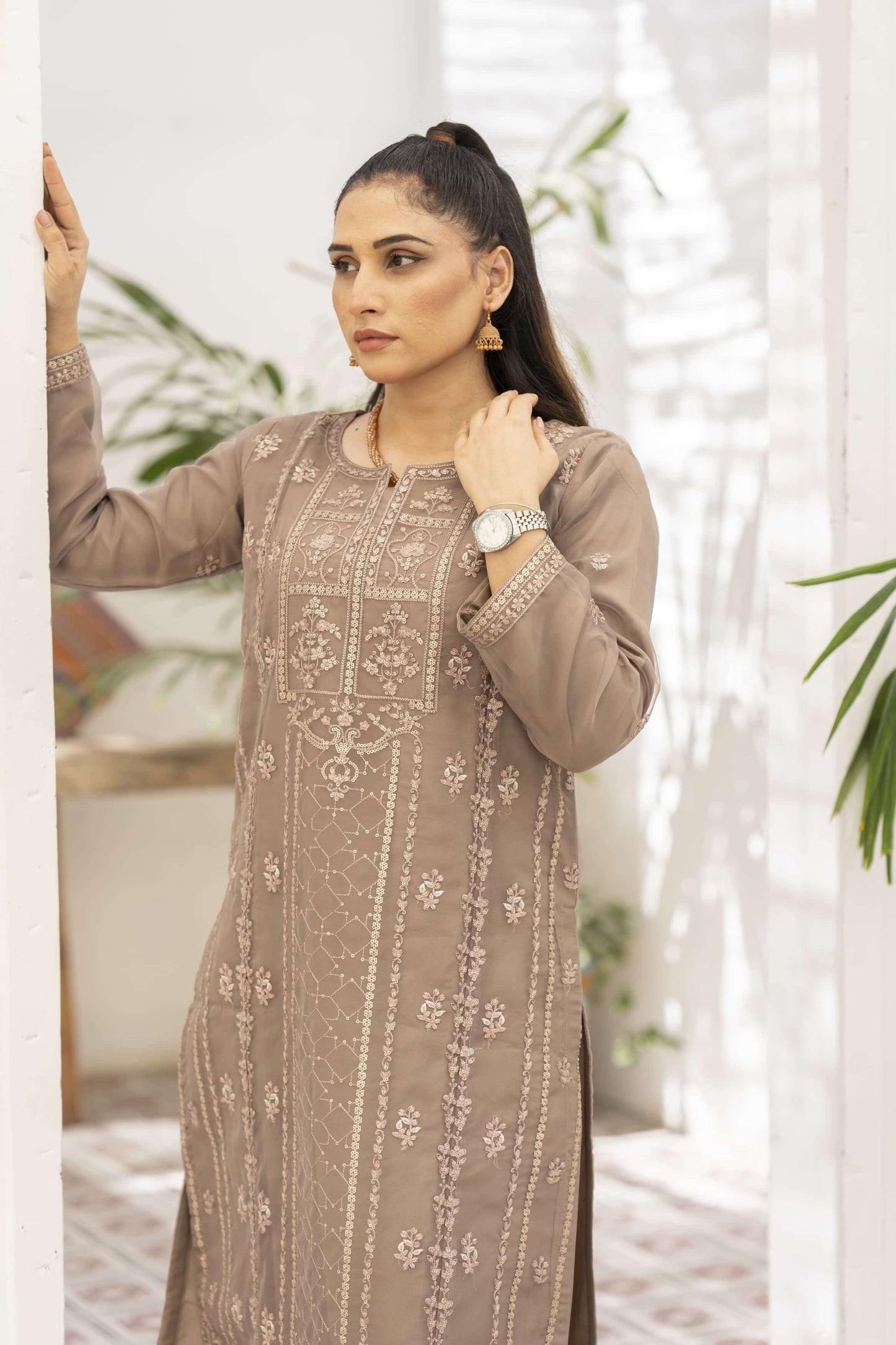 Woman wearing a brown embroidered shalwar kameez suit