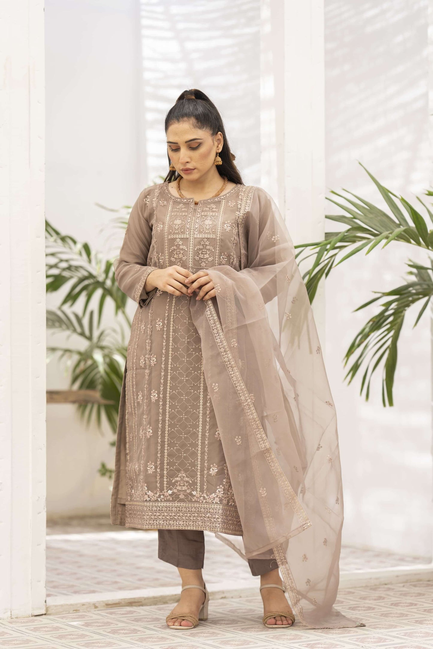 Woman wearing a traditional brwon organza outfit with dupatta