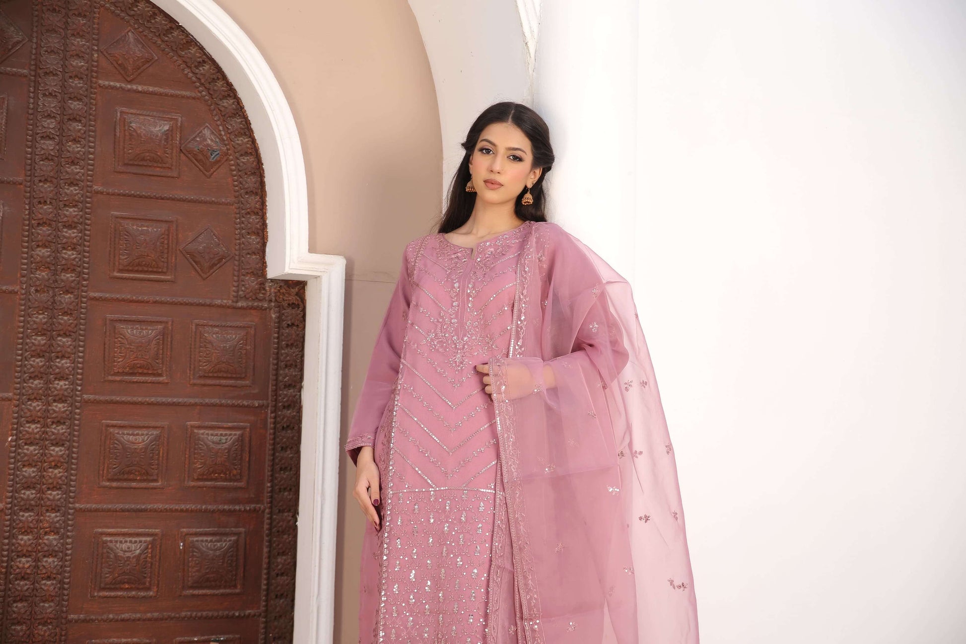 Woman in a pink traditional organza fabric shalwar kameez outfit standing clsoeup