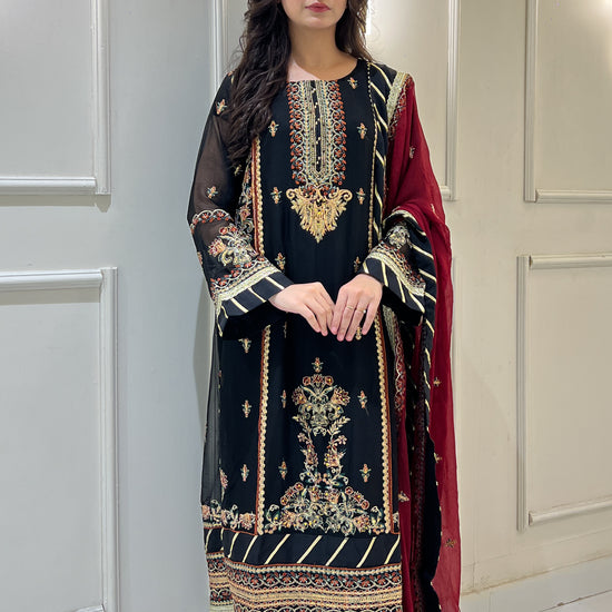 Woman wearing black chiffon embroidered shalwar kameez with maroon dupatta, twirling and showing dress in video