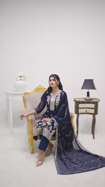 Model wearing navy blue chiffon 3-piece suit with white embroidery, showcasing flowy fabric, embroidery details, and elegant styling in motion.